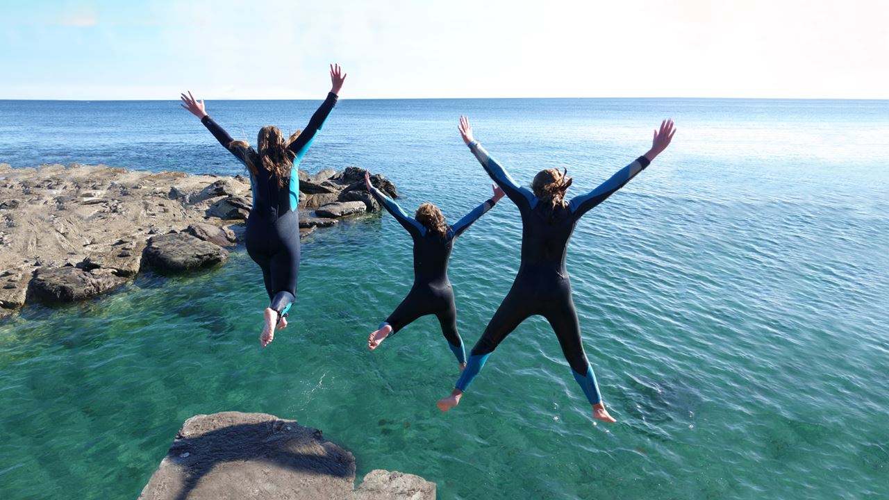 Imahe of three women leaping into the sea